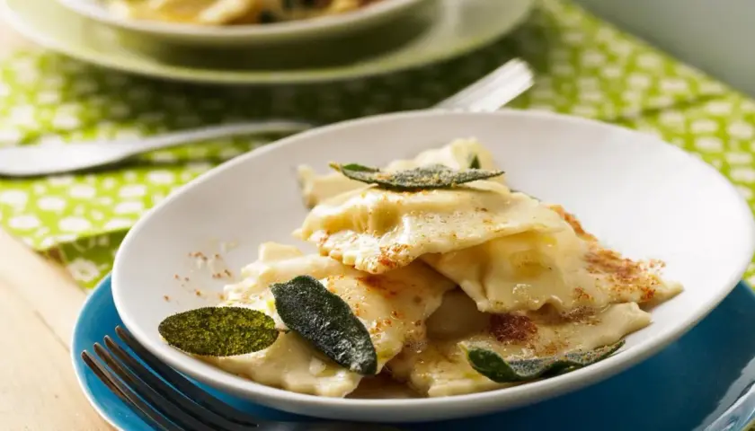 Ravioli ricotta mit Salbeibutter und zerstoßenem Pfeffer, garniert mit frischen Salbeiblättern. Ein Genuss für Feinschmecker.