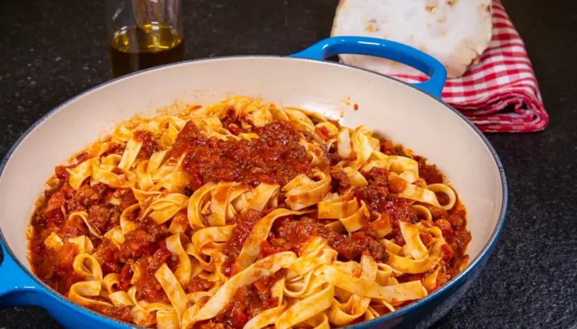 Herzhaftes Tagliatelle Bolognese, ein authentisches spaghetti bolognese rezept original, serviert in einer blauen Pfanne.