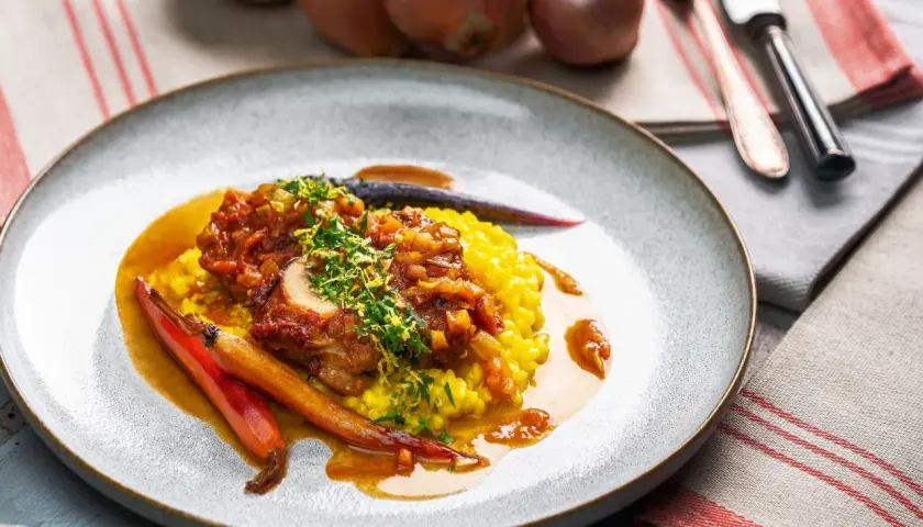 Ein köstliches Ossobuco Rezept mit zartem Kalbfleisch, serviert auf Safranrisotto und garniert mit frischen Kräutern und karamellisierten Karotten.