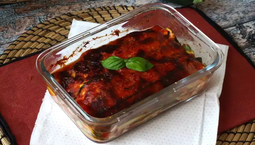 Herzhaftes Zucchini Piccata im Glasauflauf, mit Tomatensauce und Basilikum garniert.