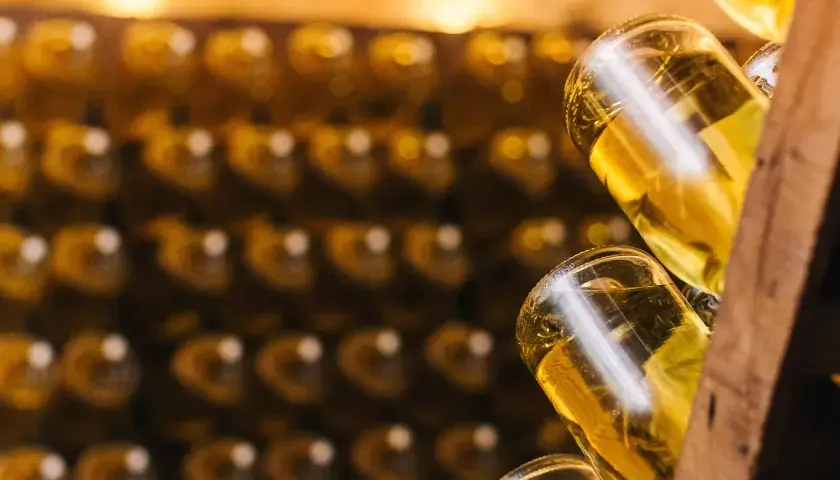 Flaschen mit goldgelbem Inhalt, vielleicht Prosecco, lagern in Regalen. Ob Prosecco schlecht werden kann, ist eine Frage der Lagerung.