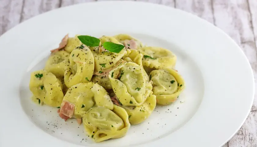 Spinat Ricotta Tortellini in cremiger Sauce, garniert mit Basilikum und schwarzem Pfeffer. Ein köstliches Gericht, das zum Genießen einlädt.