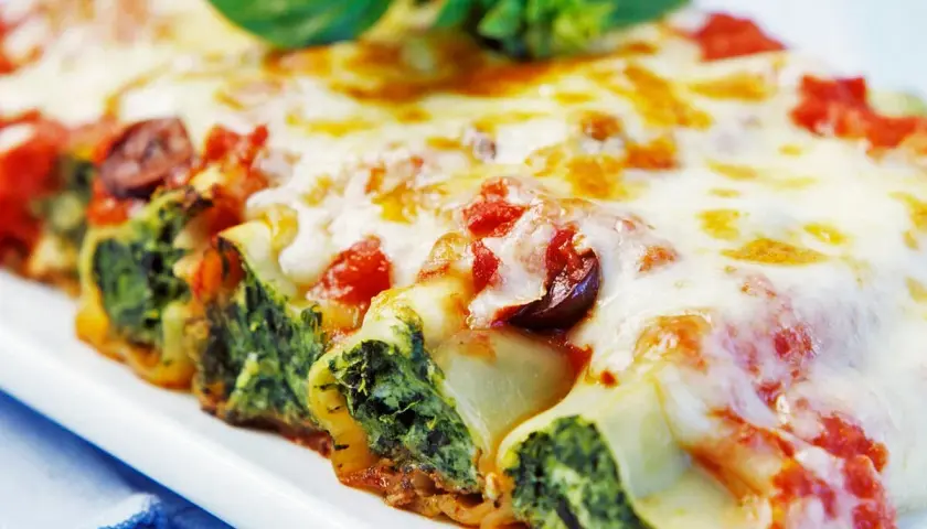 Cannelloni gefüllt mit Spinat und Ricotta, überbacken mit Tomatensauce und Käse, garniert mit Basilikum.