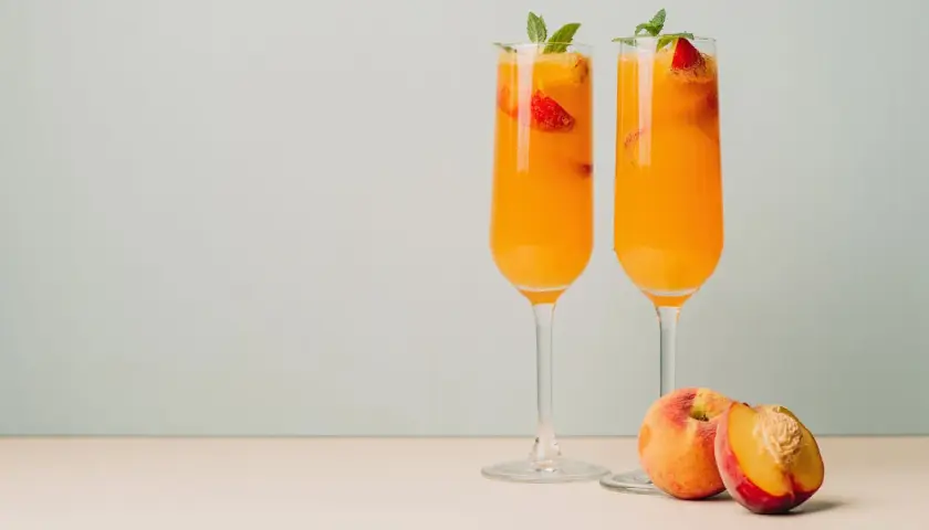 Zwei Bellini-Cocktails mit Pfirsich und Erdbeeren, garniert mit Minze. Das Bellini Rezept original ist einfach und erfrischend.