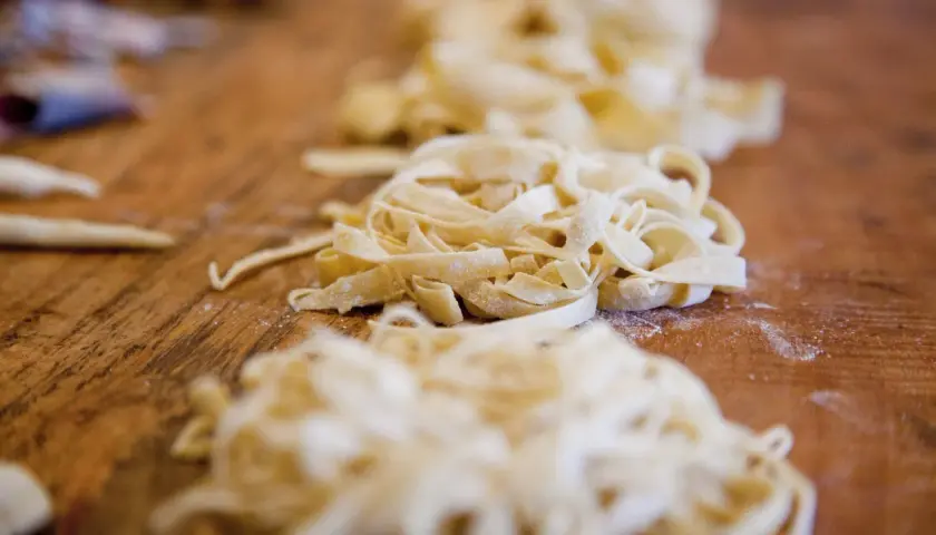 Frische Bandnudeln liegen auf einem Holztisch, bereit für ein leckeres Bandnudeln Rezept.