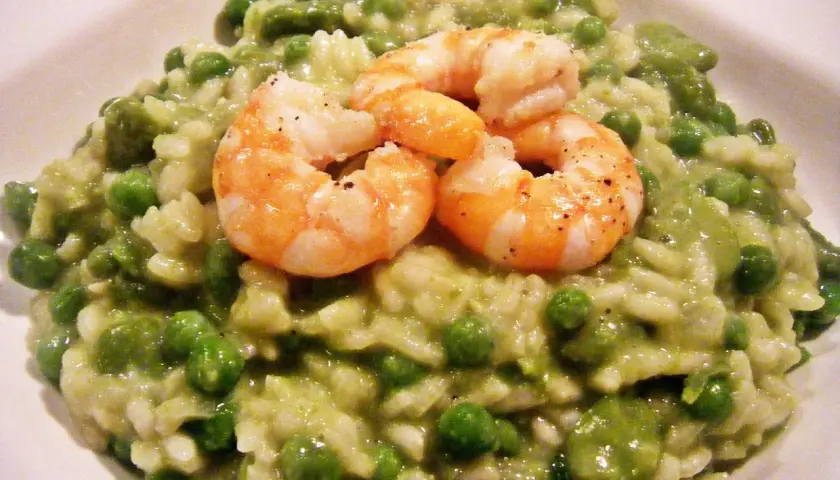Cremiges Risotto mit Erbsen und drei saftigen Garnelen, ein Genuss für Augen und Gaumen.