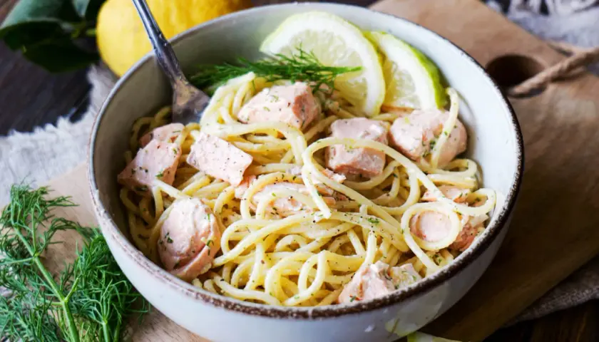 Eine Schüssel Pasta mit Lachs, garniert mit Dill und Zitronenscheiben. Ein köstliches Pasta Salmone Gericht.