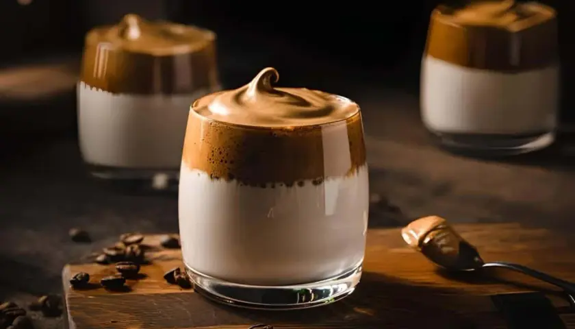 Drei Gläser mit cremigem Kaffee und Kondensmilch, garniert mit Kaffeebohnen.