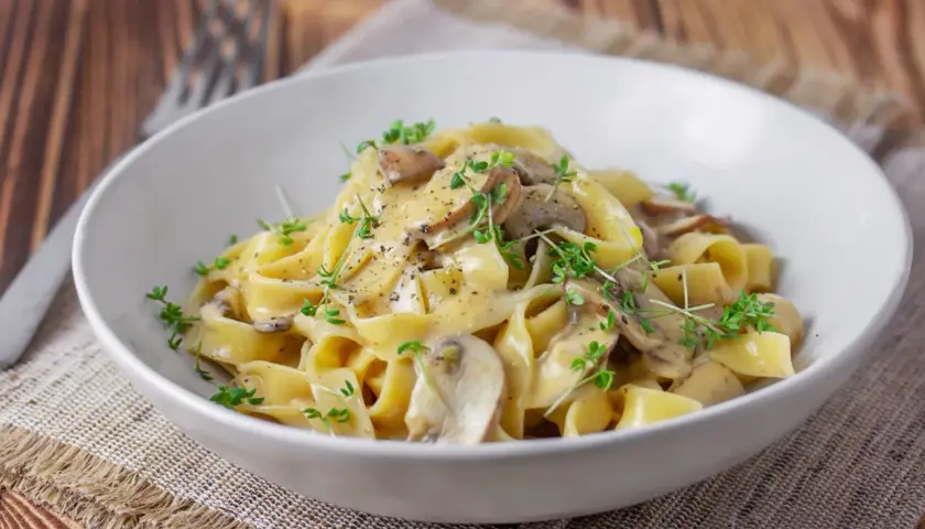 Cremige Tagliatelle mit Pilzen, garniert mit frischen Kräutern und schwarzem Pfeffer. Ein köstliches Gericht, das Lust auf mehr macht.