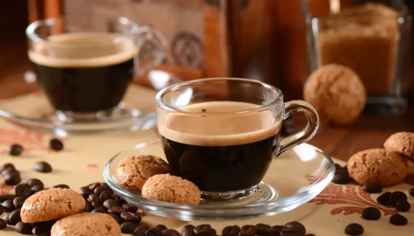 Zwei Tassen italienische Kaffeesorten mit Amarettini und Kaffeebohnen.