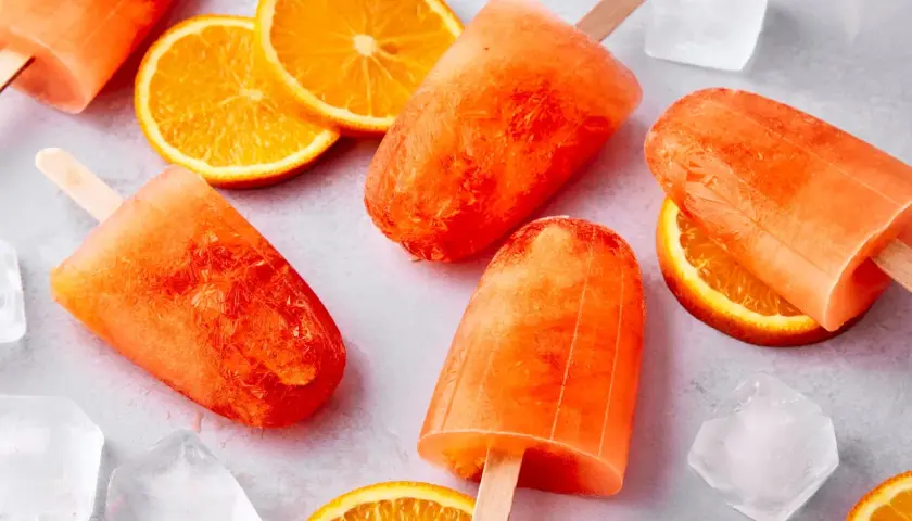 Erfrischendes Aperol Spritz Eis mit Orangenscheiben und Eiswürfeln. Perfekt für heiße Sommertage.