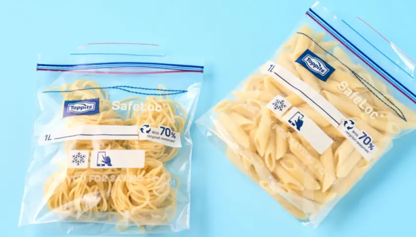 Zwei Zip-Beutel mit Nudeln, bereit zum Einfrieren. Einer enthält Spaghetti, der andere Penne.