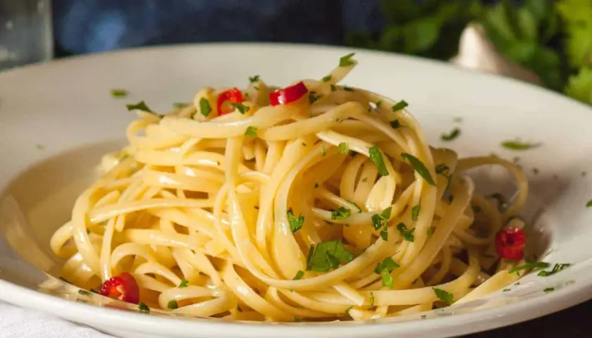 Ein Teller Spaghetti aglio olio e peperoncino, garniert mit Petersilie und roten Chilistückchen.