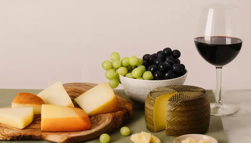 Käseplatte mit Trauben und Rotwein. Die ideale **Primitivo Trinktemperatur** wird durch die kühle Präsentation unterstrichen.