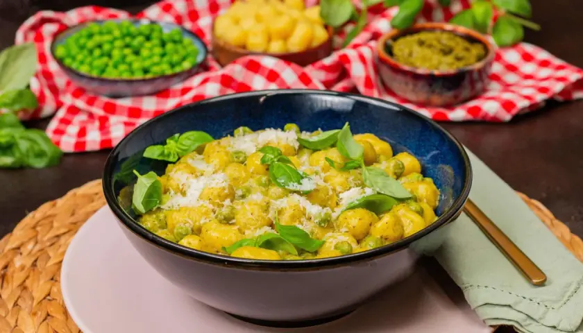 Gnocchi mit Erbsen und Parmesan in cremiger Pesto-Sauce, garniert mit frischem Basilikum.