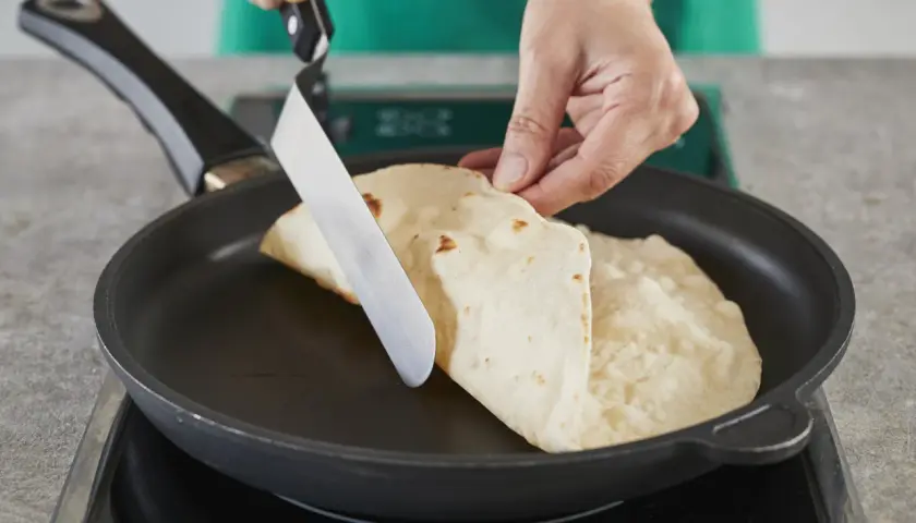 Hände falten Piadinas in einer Pfanne für ein einfaches Piadina Rezept.