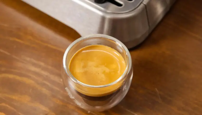 Ein frisch gebrühter Espresso Freddo in einem Glas auf Holztisch.