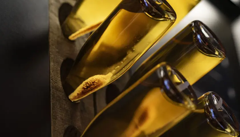 Flaschen mit Hefeablagerungen im Rüttelpult, ein Zeichen für die traditionelle Methode Champenoise.