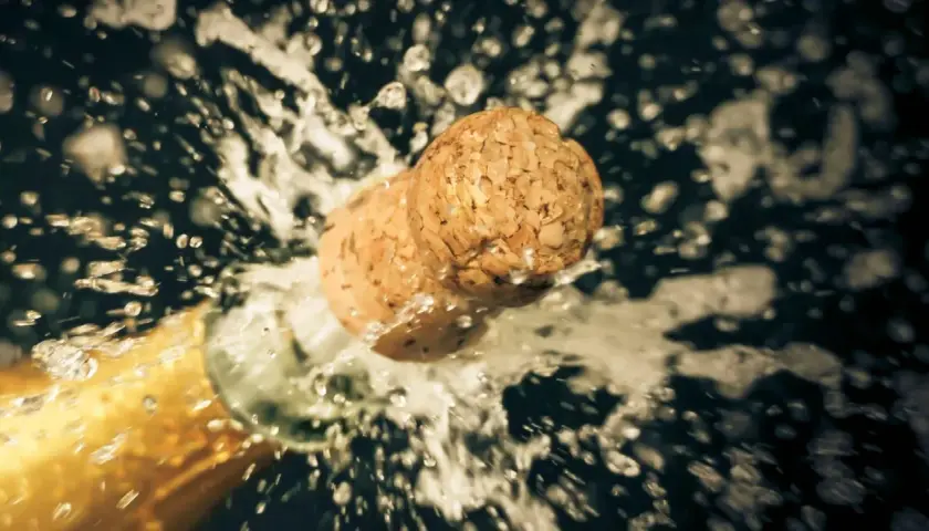 Champagnerkorken spritzt aus der Flasche, ein Moment des Feierns, der zeigt, wie wichtig es ist, Champagner richtig zu lagern.