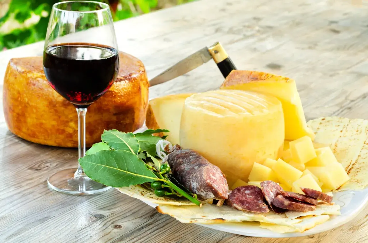 Ein Glas Rotwein, passend zu Käse und Salami. Der Wein könnte aus der Nebbiolo Traube stammen.