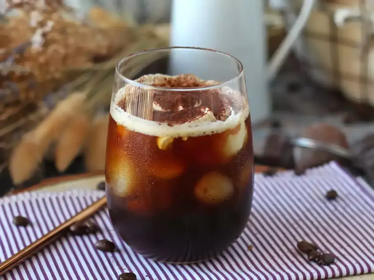 Erfrischender Eiskaffee mit Sahne und Kakaopulver, perfekt für heiße Tage. Tolle Inspiration für Kaffee Rezepte.