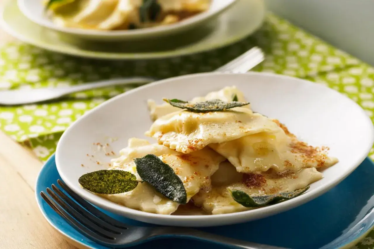 Ravioli ricotta mit Salbeibutter und zerstoßenem Pfeffer, garniert mit frischen Salbeiblättern. Ein Genuss für Feinschmecker.