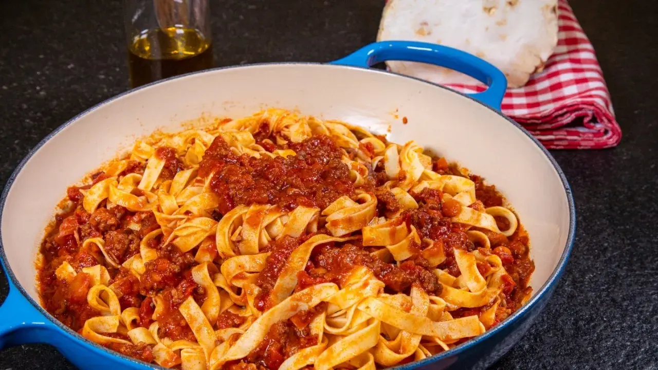 Herzhaftes Tagliatelle Bolognese, ein authentisches spaghetti bolognese rezept original, serviert in einer blauen Pfanne.