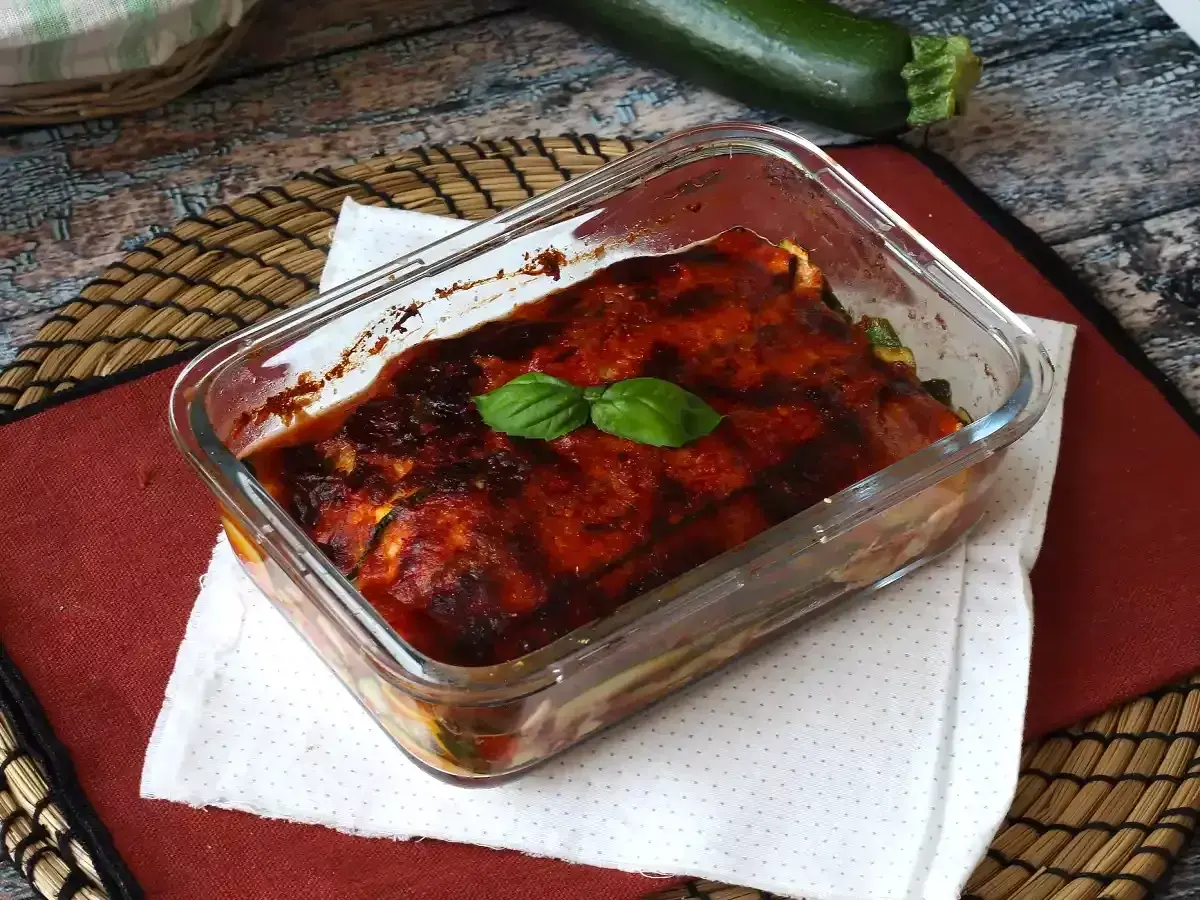 Herzhaftes Zucchini Piccata im Glasauflauf, mit Tomatensauce und Basilikum garniert.