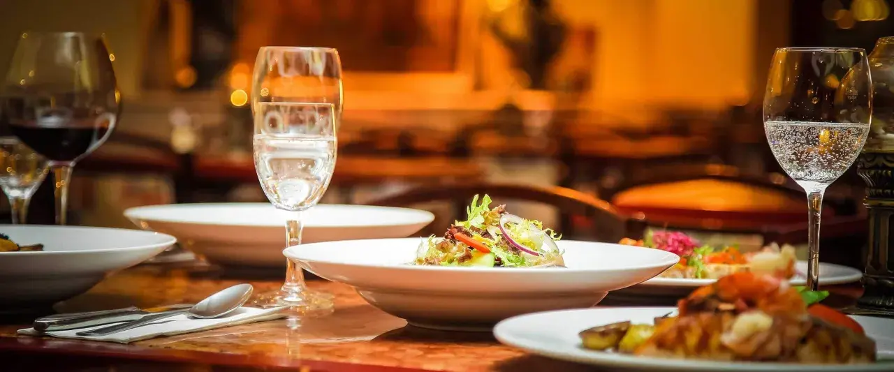 Ein gedeckter Tisch mit Speisen und Gläsern, bereit für ein köstliches Essen mit Wein zum Essen.
