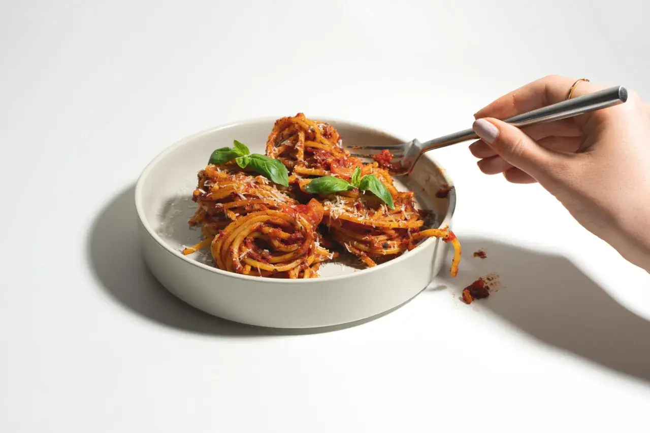 Ein Teller mit Spaghetti, garniert mit Basilikum und Parmesan. Verschiedene Nudel-Sorten sind hier als köstliche Mahlzeit präsentiert.