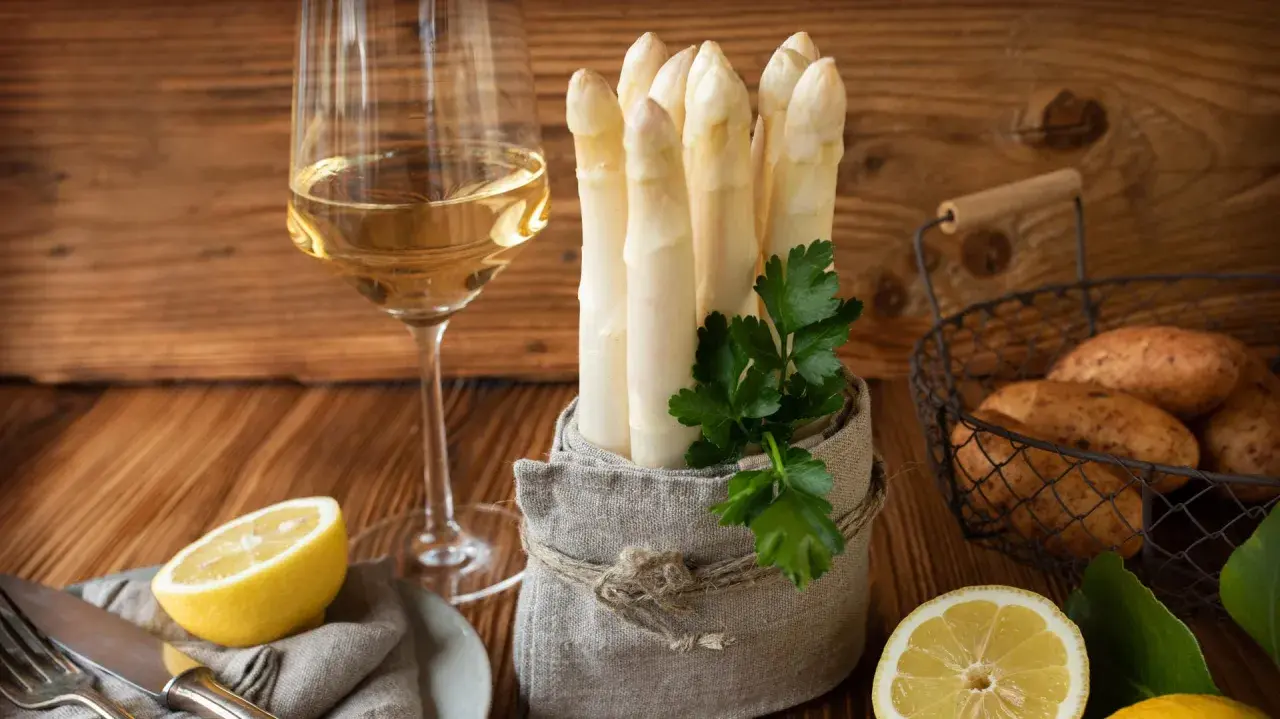 Ein Glas Weißwein neben frischem Spargel, Kartoffeln und Zitronen. Die perfekte Kombination, um die Frage zu beantworten: welchen Wein zu Spargel.
