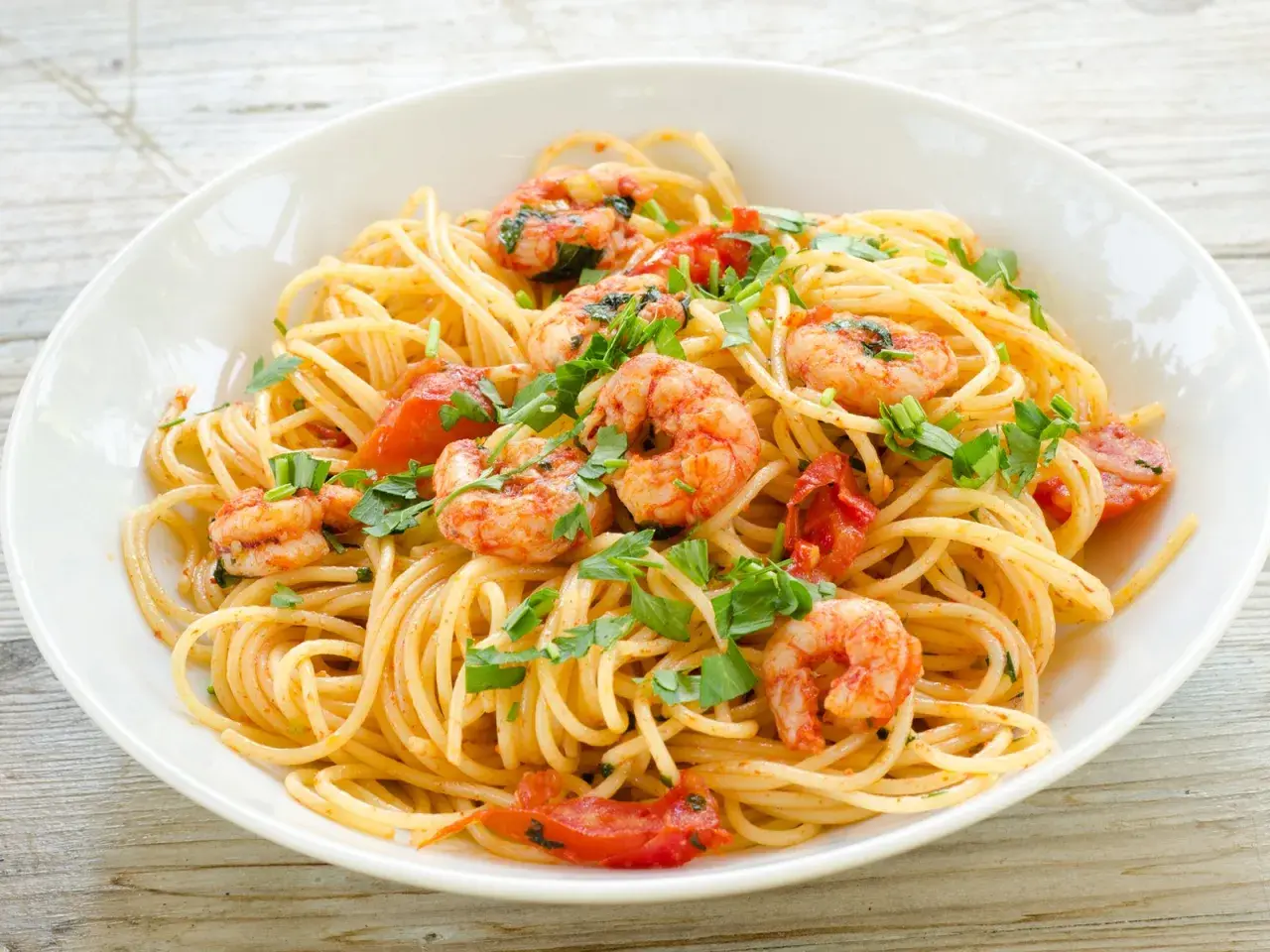 Ein Teller Spaghetti Frutti di Mare Rezept Original mit Garnelen, Tomaten und Petersilie.