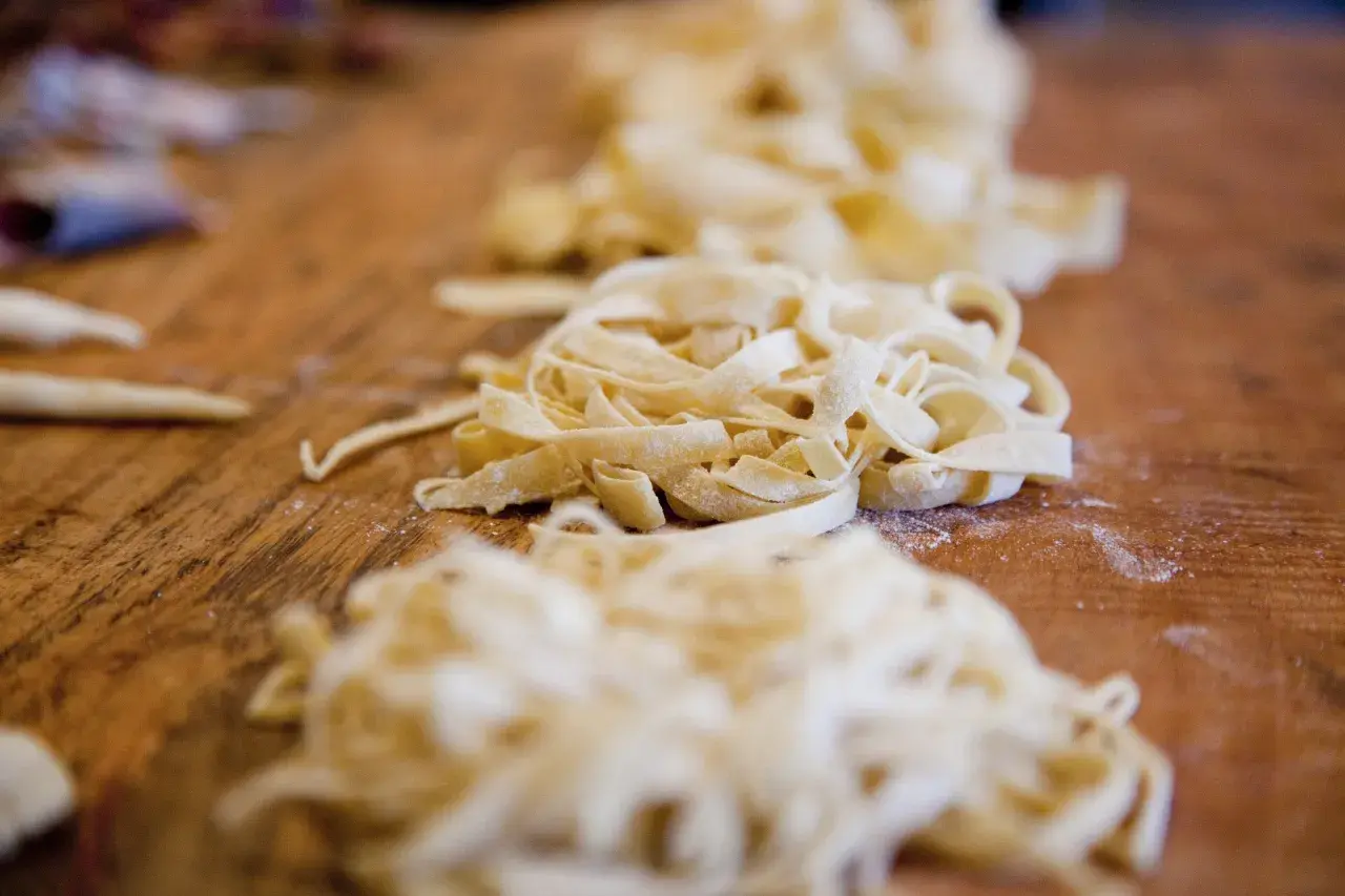 Frische Bandnudeln liegen auf einem Holztisch, bereit für ein leckeres Bandnudeln Rezept.