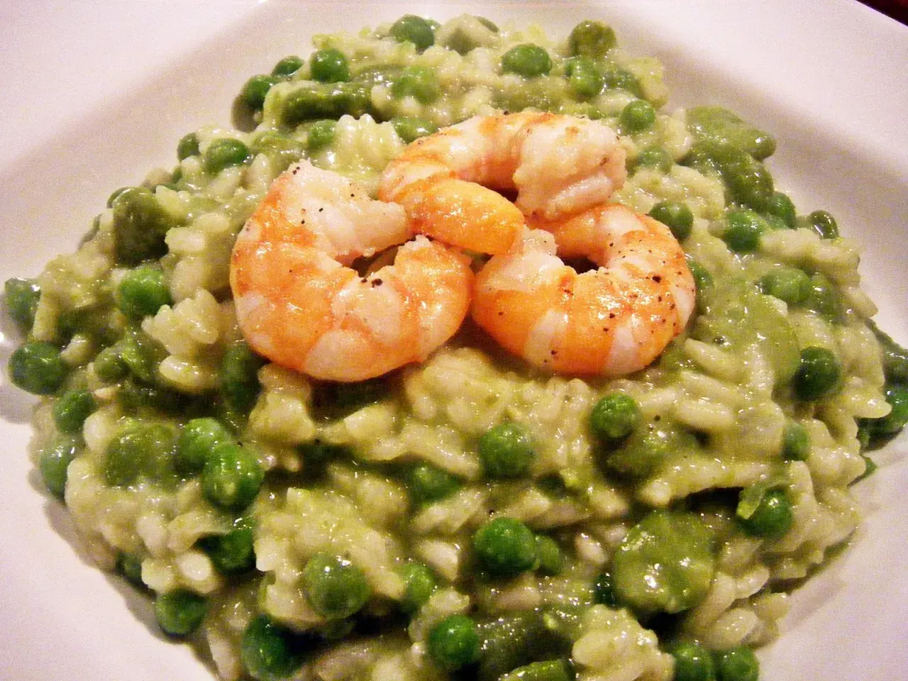 Cremiges Risotto mit Erbsen und drei saftigen Garnelen, ein Genuss für Augen und Gaumen.