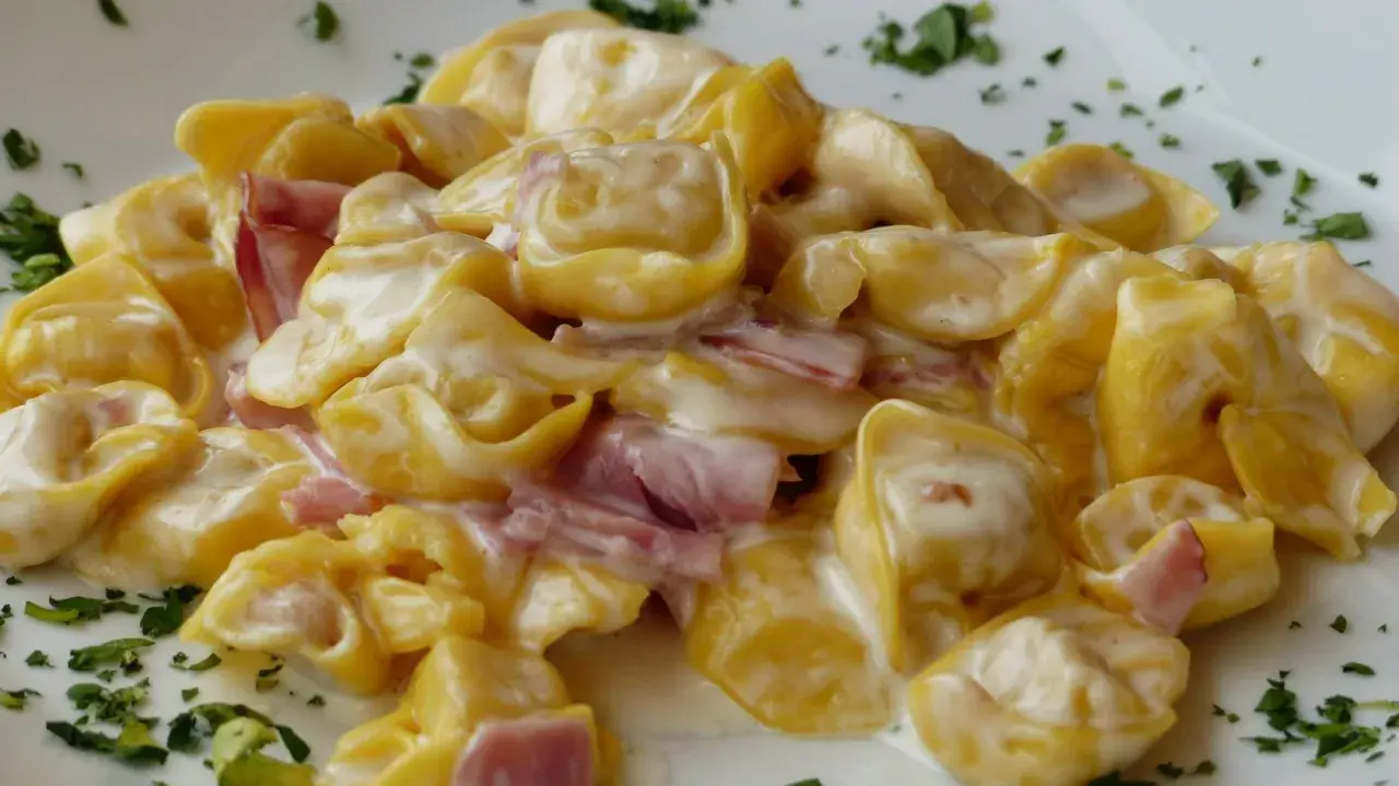 Cremige Tortellini mit Schinken in einer hellen Sauce, garniert mit Petersilie. Perfekt zum Tortellini einfrieren für später.