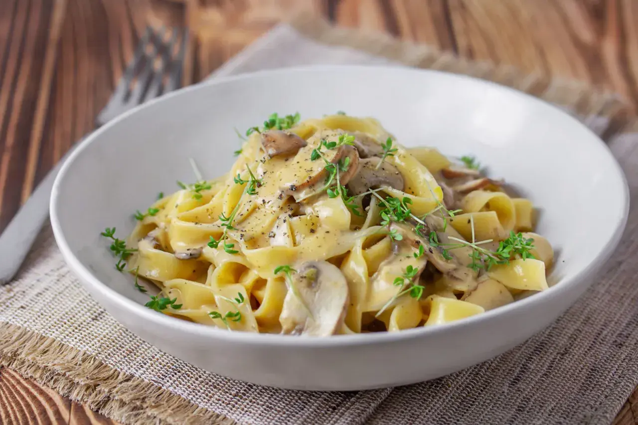 Cremige Tagliatelle mit Pilzen, garniert mit frischen Kräutern und schwarzem Pfeffer. Ein köstliches Gericht, das Lust auf mehr macht.