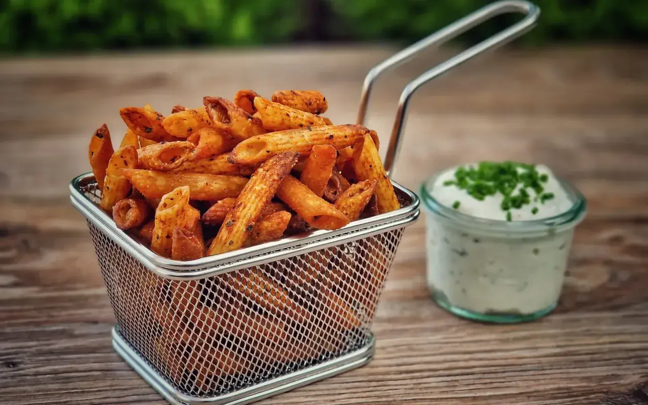 Knusprige Pasta Chips in einem Metallkorb, daneben ein Dip mit Schnittlauch. Ein leckerer Snack für zwischendurch.