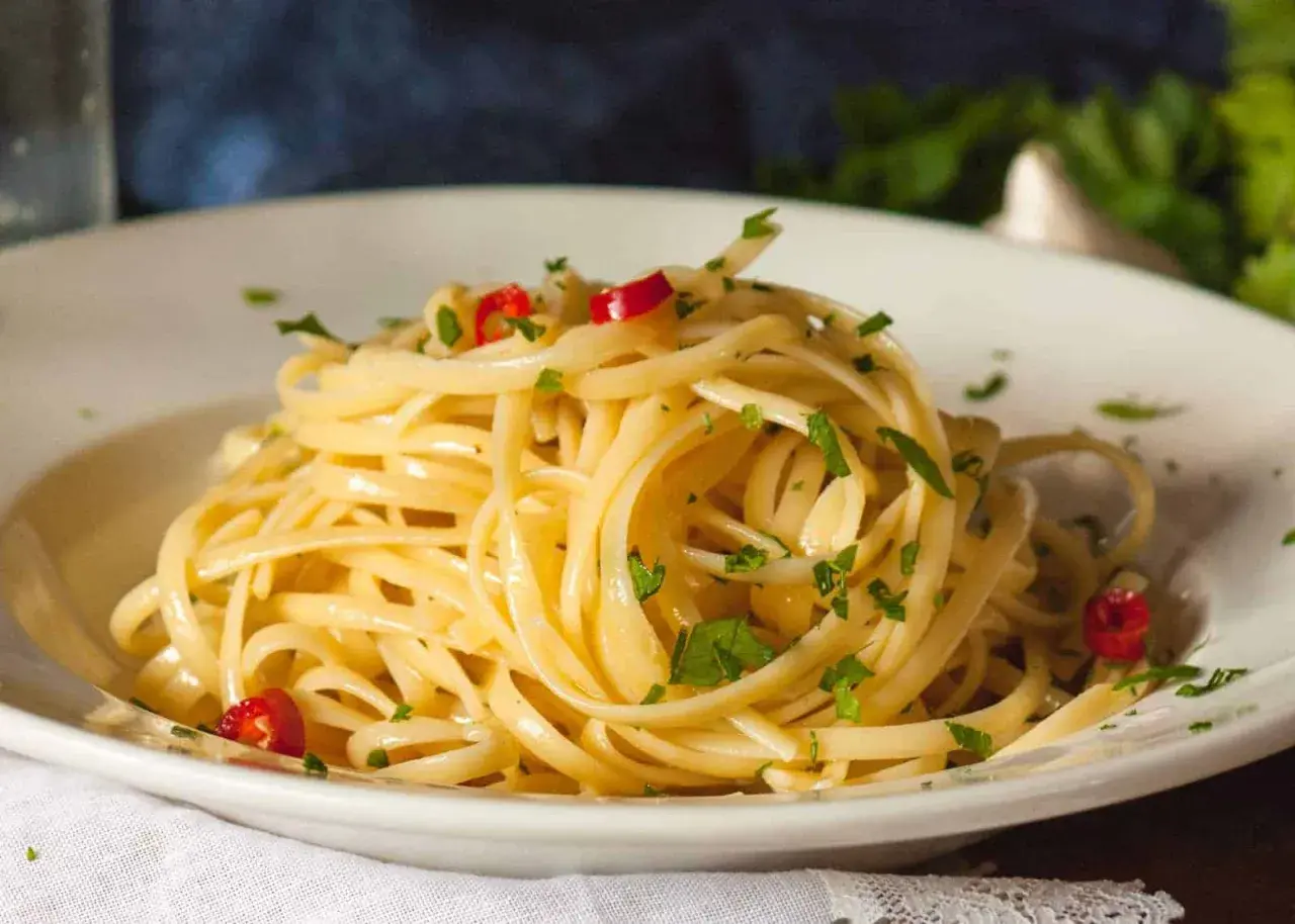 Ein Teller Spaghetti aglio olio e peperoncino, garniert mit Petersilie und roten Chilistückchen.