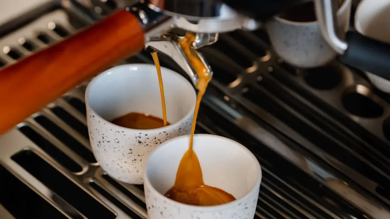 Frisch gebrühter Espresso fließt in zwei Tassen. Hoffentlich ist er nicht zu bitter.