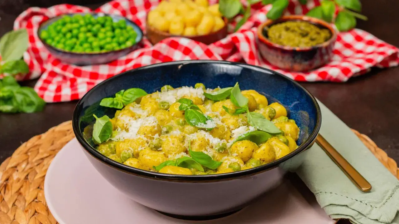 Gnocchi mit Erbsen und Parmesan in cremiger Pesto-Sauce, garniert mit frischem Basilikum.