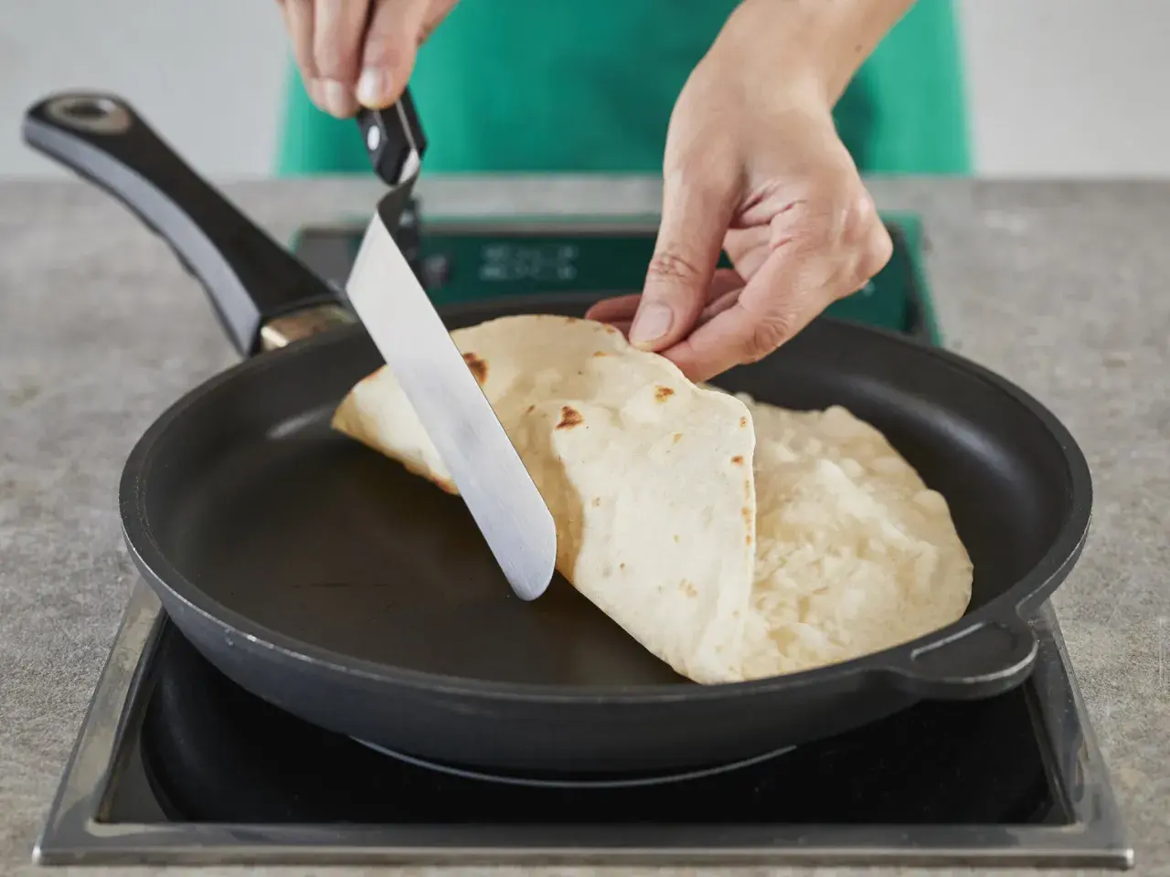 Hände falten Piadinas in einer Pfanne für ein einfaches Piadina Rezept.