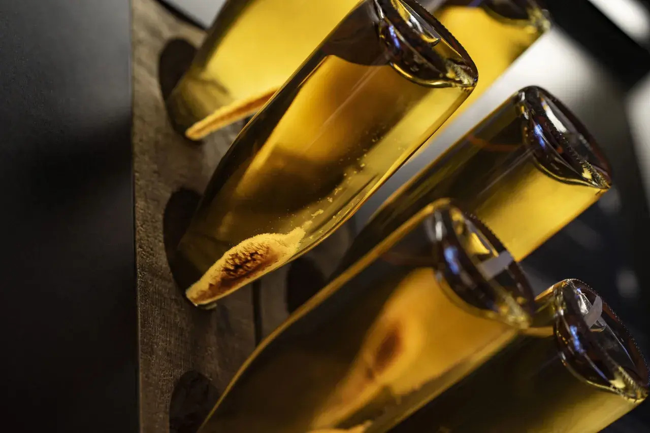 Flaschen mit Hefeablagerungen im Rüttelpult, ein Zeichen für die traditionelle Methode Champenoise.