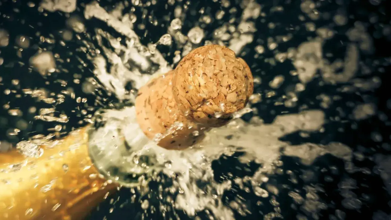 Champagnerkorken spritzt aus der Flasche, ein Moment des Feierns, der zeigt, wie wichtig es ist, Champagner richtig zu lagern.