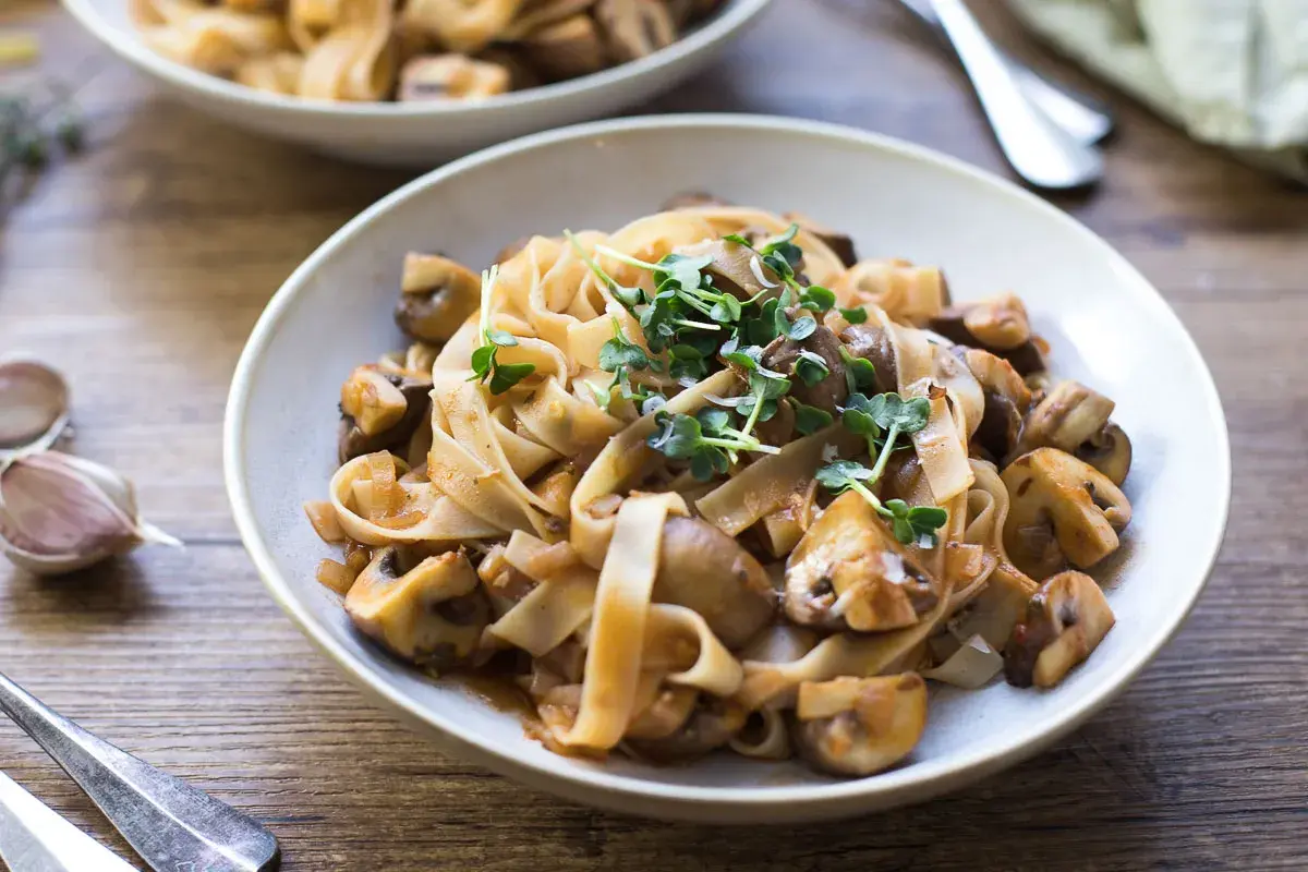 Herzhafte Pasta mit Pilzen, ein klassisches italienisches Gericht, garniert mit frischen Sprossen.