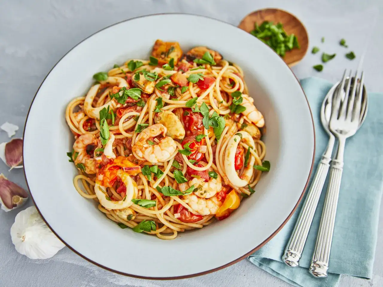 Spaghetti Frutti di Mare: Ein authentisches Rezept mit Garnelen, Tintenfischringen und Muscheln in Tomatensauce, garniert mit Petersilie.