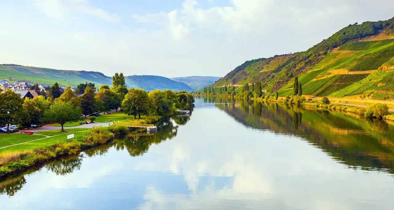 Flusslandschaft mit Weinbergen, die den einzigartigen terroir wein widerspiegeln. Grüne Hänge, ein Dorf und ein ruhiger Fluss.