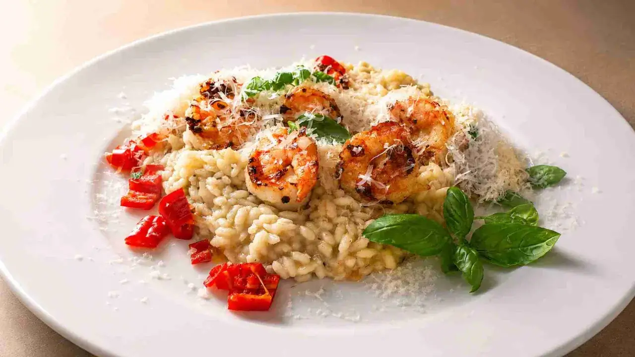 Cremiges Zitronen Risotto mit gegrillten Garnelen, roten Paprikawürfeln und frischem Basilikum, bestreut mit Parmesan.