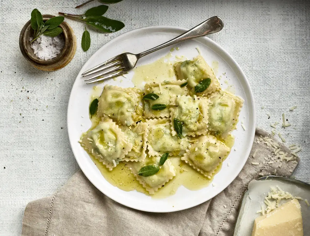 Ravioli mit Spinat und Ricotta, betr&auml;ufelt mit Butter und garniert mit Salbeibl&auml;ttern und Parmesan.