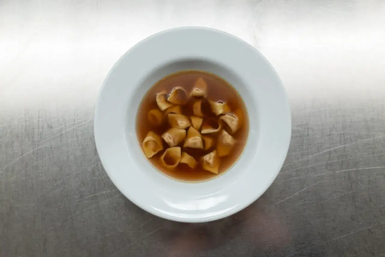 Eine Schüssel mit dampfenden Tortellini in Brodo, ein klassisches italienisches Gericht, das Wärme und Komfort verspricht.