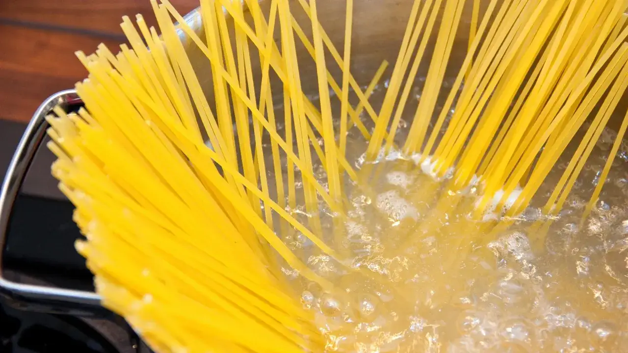 Gelbe Spaghetti kochen in sprudelndem Wasser. Der Topf ist fast voll mit den langen Nudeln.